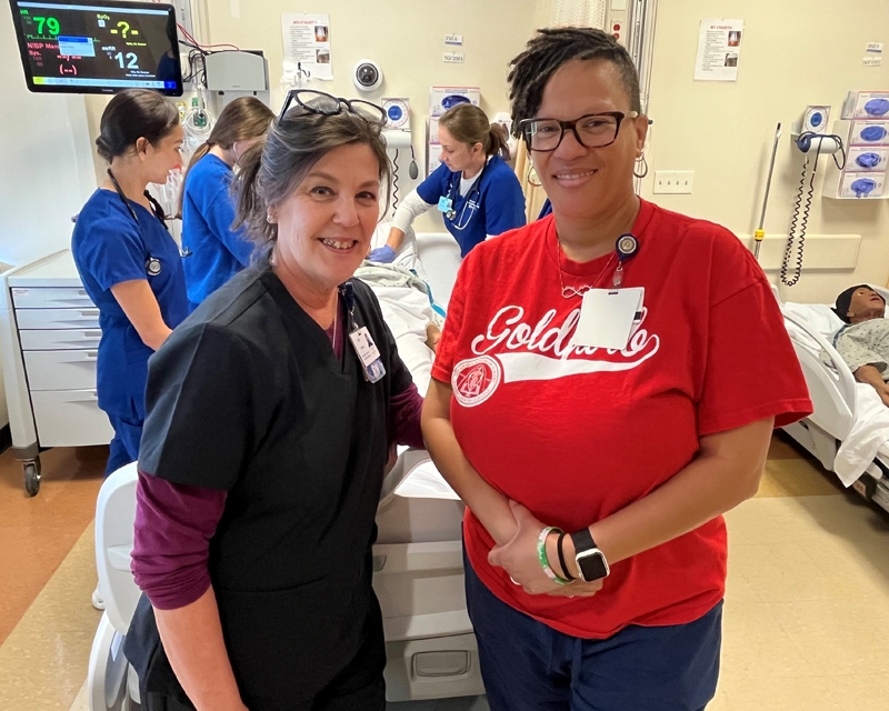 Goldfarb simulation specialists Zoe dePenaloza and  LaTreece Norwood standing in a simulation classroom.