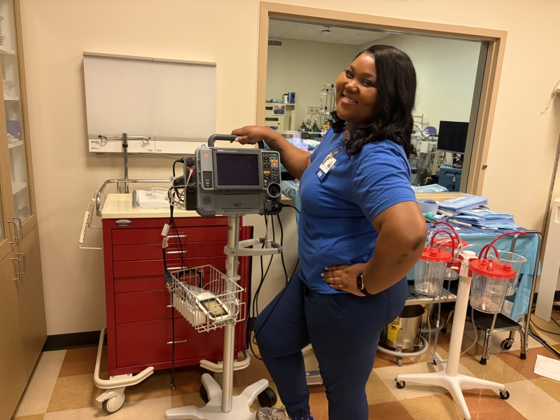 Christina Palmer poses with equipment in the health assessment lab, where she previously worked as an instructor.