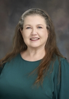 A portrait of Janice Bragg smiling with a green dress sweater.