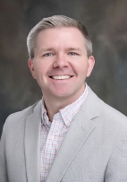 Lucas Hahn smiling in a gray suit jacket.