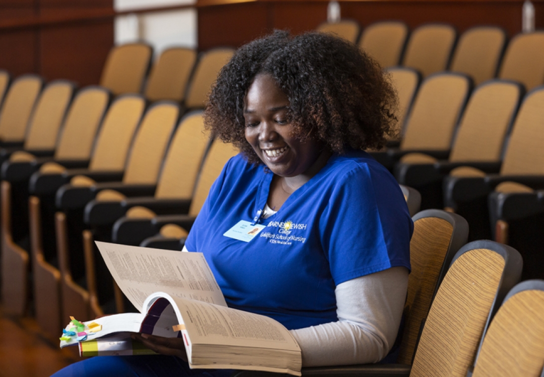 Woman student in class reading book.