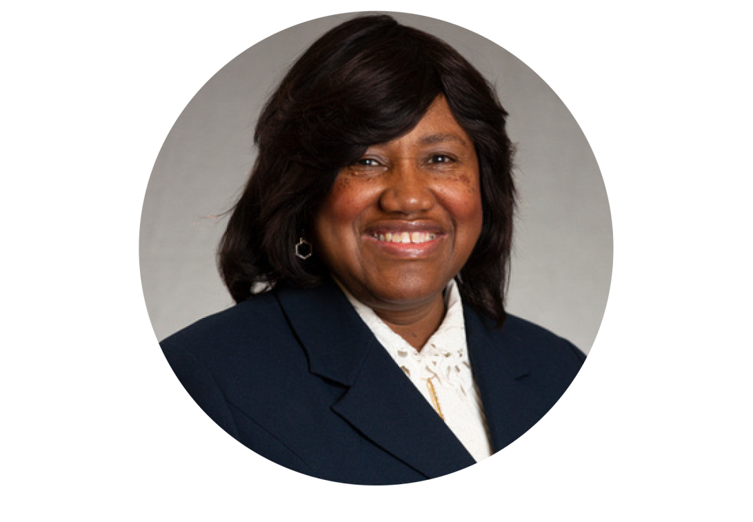 A portrait of Tamara Otey smiling with a black dress coat and white blouse.