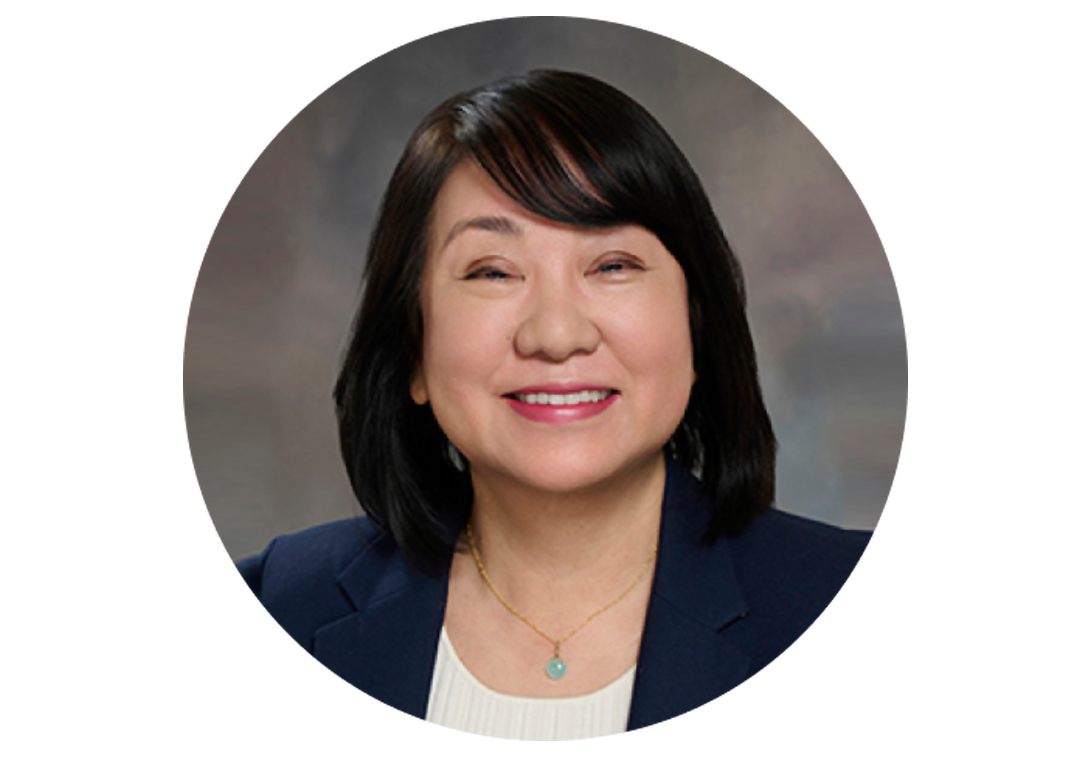 Masako Mayahara smiling at the camera with a black coat and white blouse.