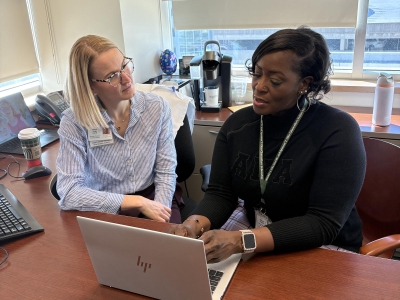 Two women sitting in front of laptop computer.
