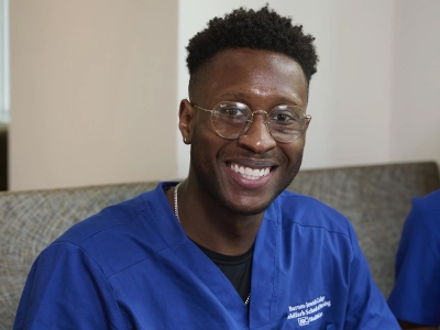 Devin Macklin, a  Goldfarb student in a scrub sitting down and smiling.